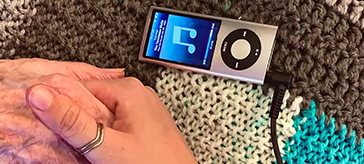 photo of a young person's hand touching a senior's hand beside an ipod with music playing (photo credit:Sierra Gladu)