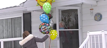 a female team member from Waterford Barrie delivering a bouquet of balloons to a senior