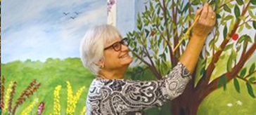 image of a resident of Victoria Manor is drawing on the wall mural