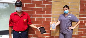 Orillia Rotarian Michel Rousseau presents tablets to Sarah Galbraith of Spencer House.