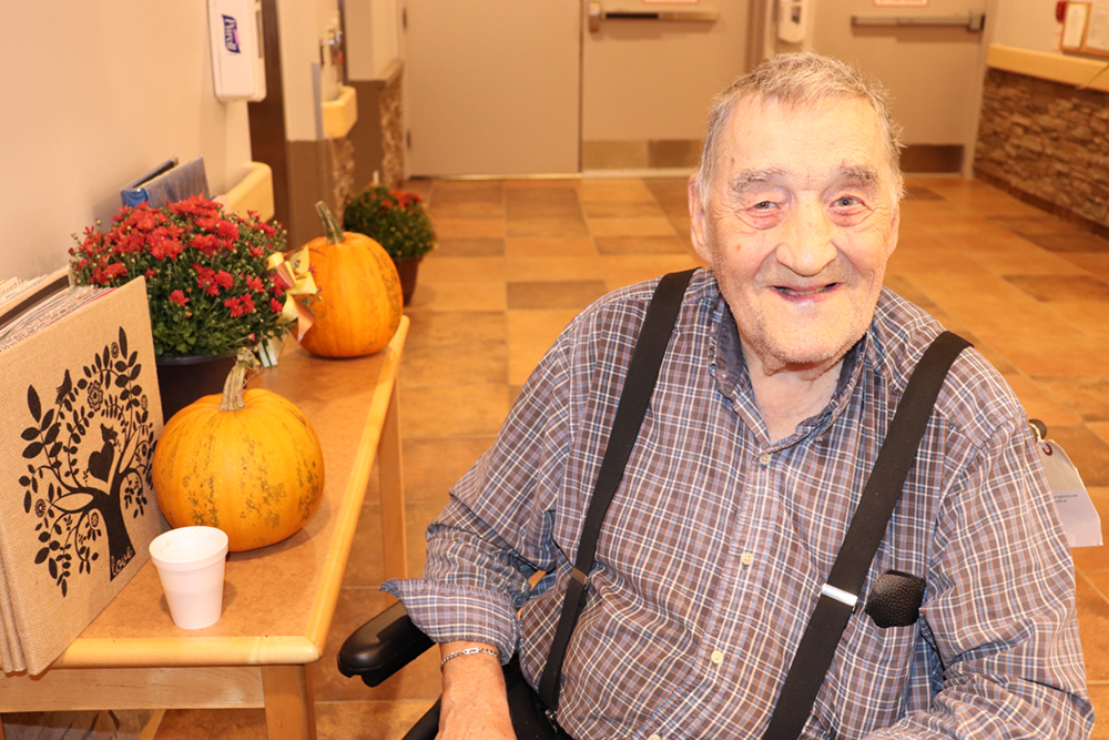 A gentleman sitting beside Halloween decorations.