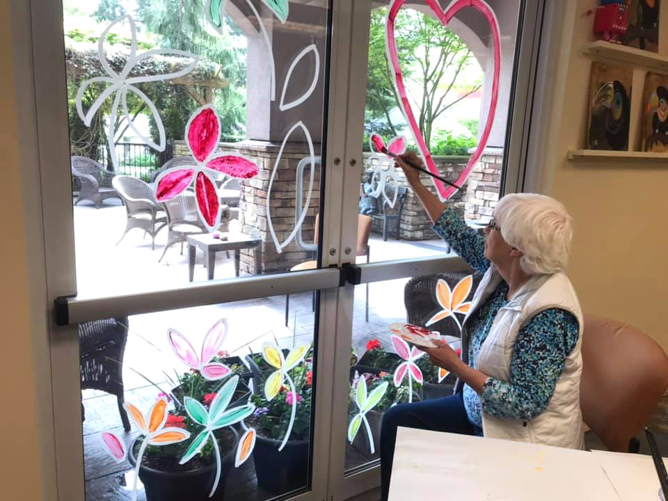 A lady drawing art on the windows. 