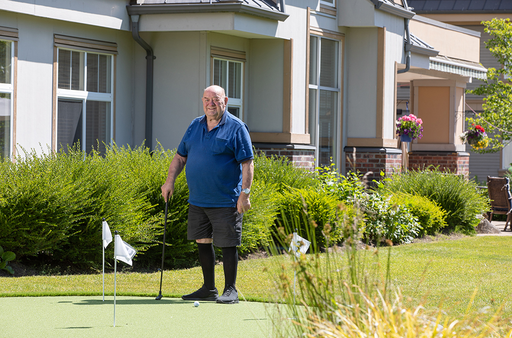Older man plays golf in the garden of a residence
