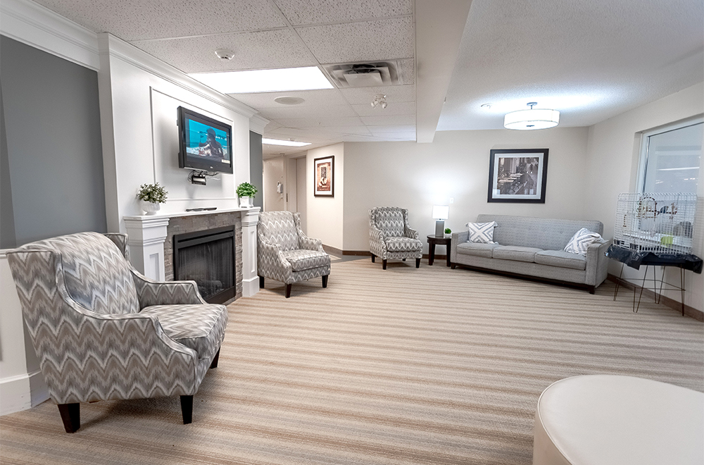 Seating area with a fireplace and a bird cage on the right at Masonville Manor Retirement Residence in London