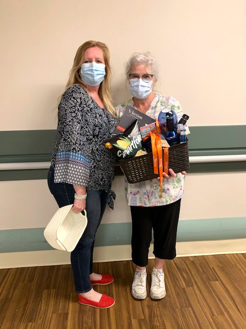 A team member and a resident holding a gift basket. 