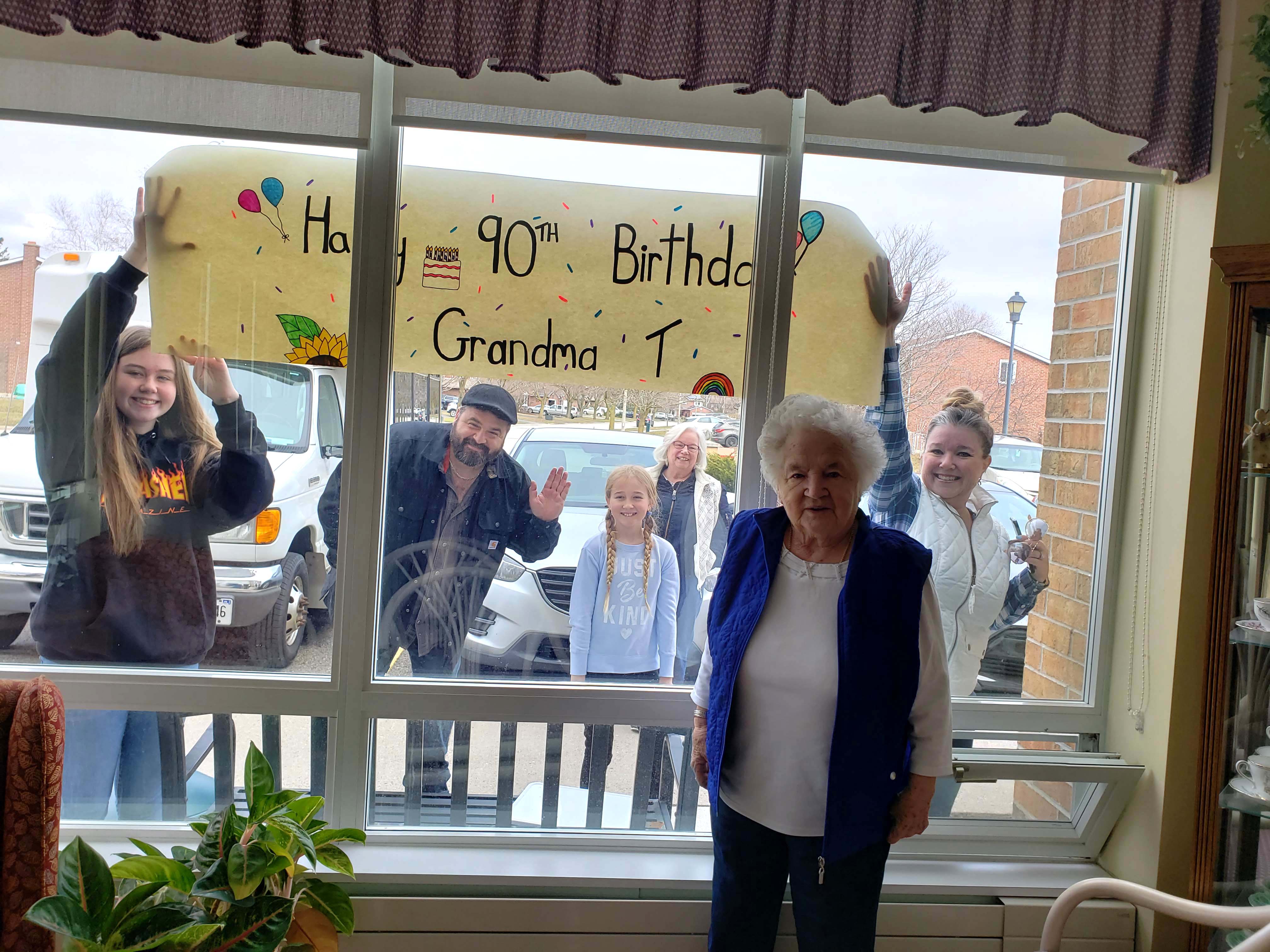 A resident family posing outdoors for a photo together to celebrate resident's 90th birthday.