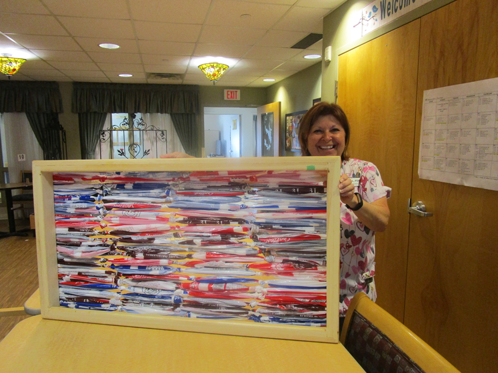 A team member holding up a piece of art made from recycled milk bags.