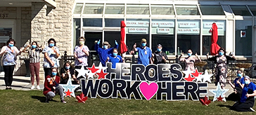 group photo of team members standing behind the Heroes signage at the front entrance of Quinte Gardens