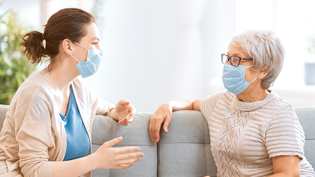 Adult daughter and senior parent wearing face masks