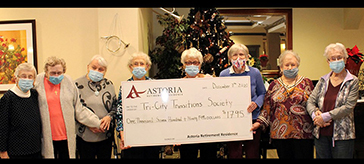 Members of Astoria Retirement's knitting circle in Port Coquitlam hold up a giant cheque for nearly $1,800 to the Tri-City Transitions Society from its 2021 craft fair and auction for charity.
