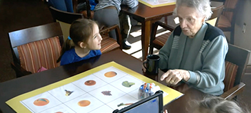 photo of a resident at Royale Place enjoying time with the little girl from École Rideau P.S. 