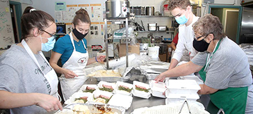 image of Martha's Table staff, from left, Reanna King, Jersey Phin, Gavin Lalande and Betty Ann Revelle, prepare takeout meals donated by Sienna Senior Living.