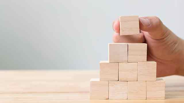 hand shown stacking building blocks into a pyramid