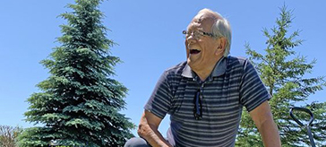 older man smiling with ducks by his side in a garden of a residence