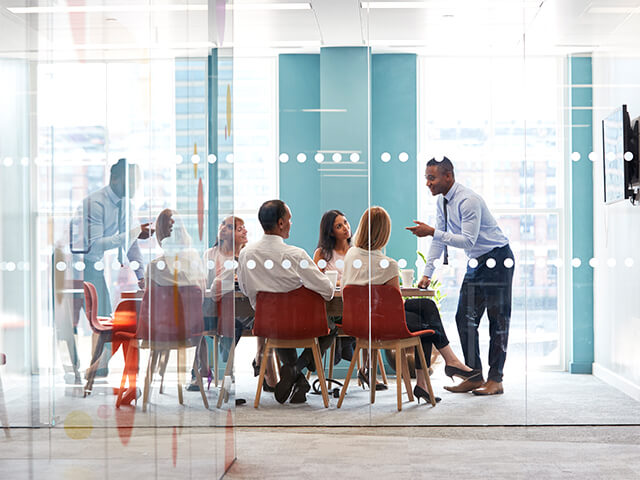 image of a young male boss stands leaning on table at business meeting
