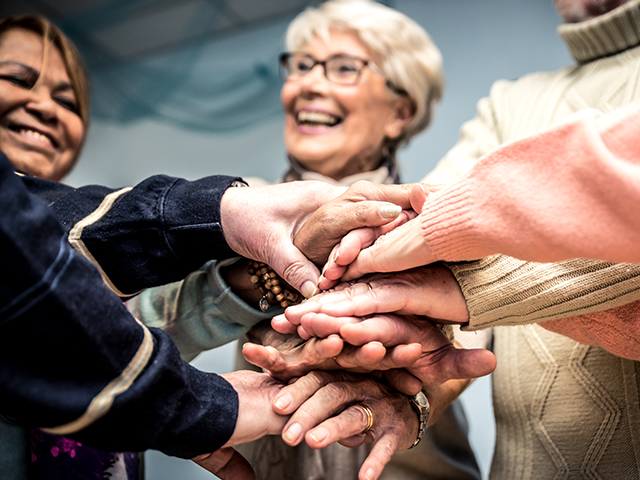 image of a group of seniors putting their hands together in a huddle
