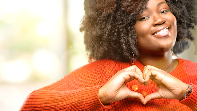 image of a young African women holding a heart shape and smiling