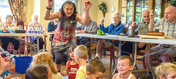 image of MaryLou Primeau encourages the children to make some rhythm with little shakers.