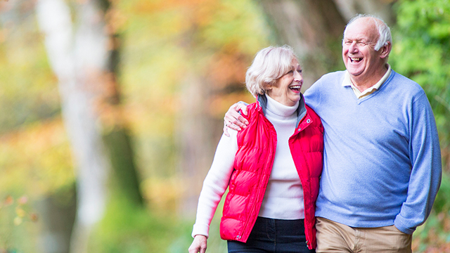 A happy senior couple taking a walk in the forest in an outdoor setting.