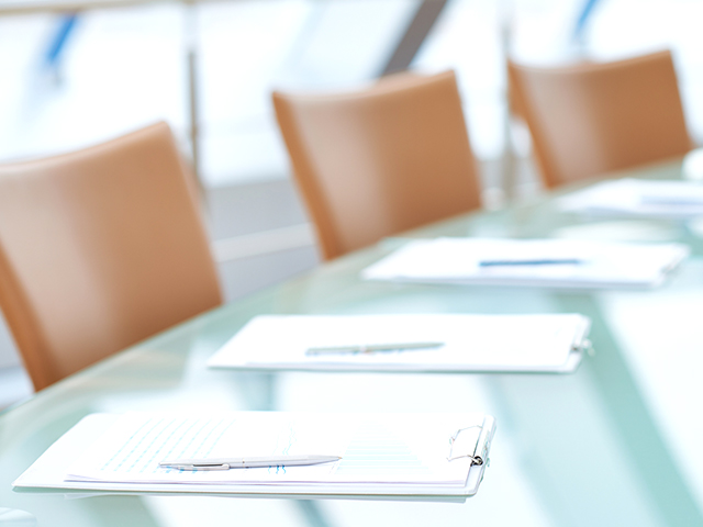 image of businessman's hands covering paper team on wooden table