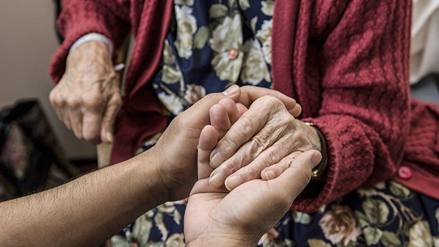 Elderly woman holds hand with nurse